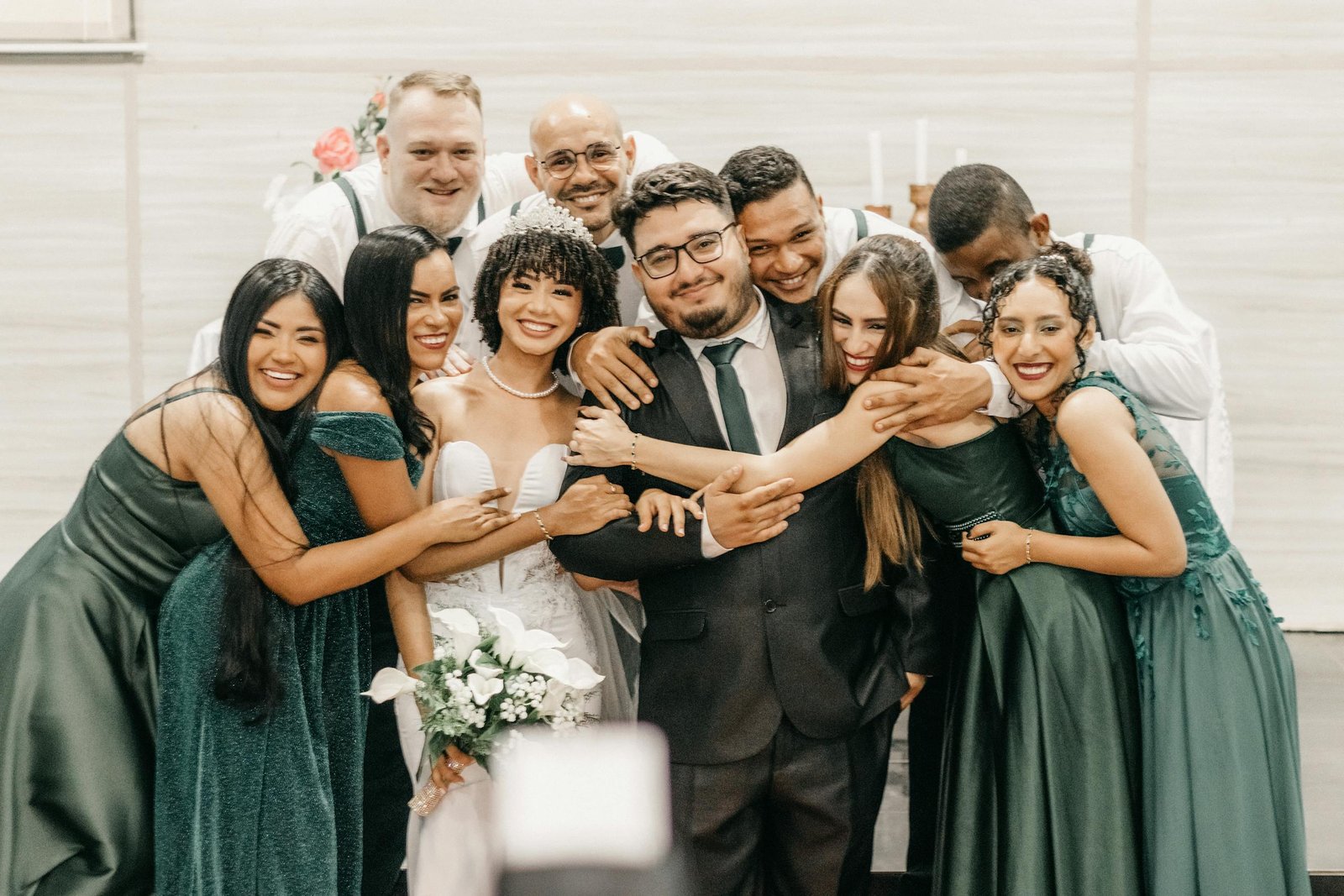 A joyous wedding group photo capturing the bride, groom, and friends celebrating together with laughter and connection