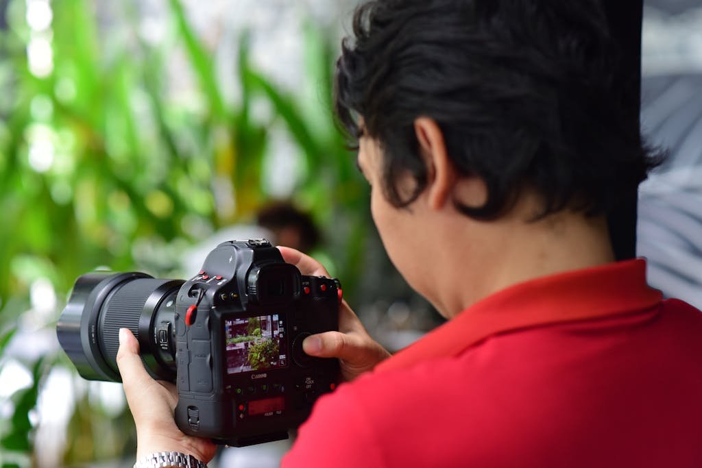 A photographer focuses on capturing nature using a DSLR camera in an indoor setup with green plants